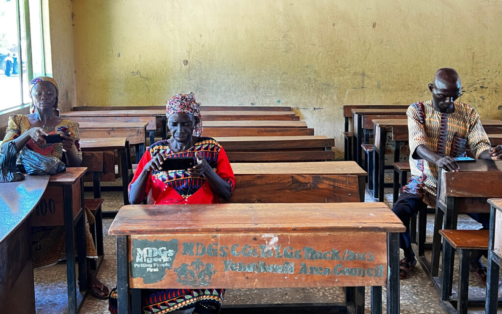 Three persons sitting in a classroom and using tablet computers