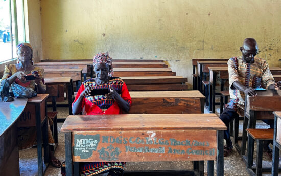 Three persons sitting in a classroom and using tablet computers