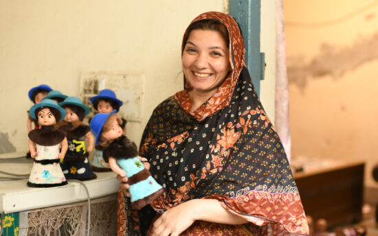 Person smiling at the camera and holding a doll